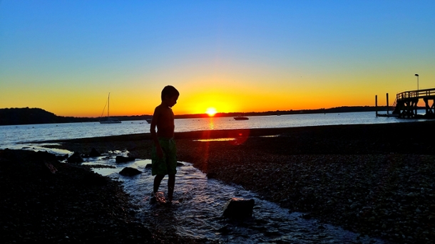silhouette of a boy at the beach at sunset